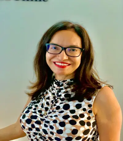 A woman with glasses and a polka dot shirt.