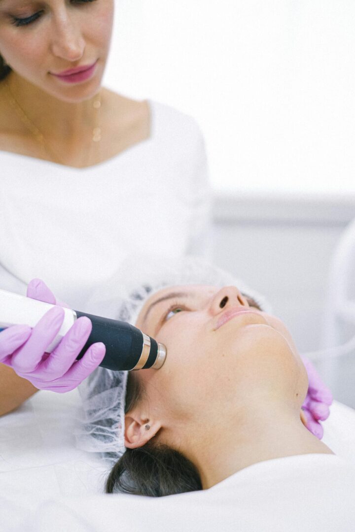 A woman getting her face cleaned with an electric device.